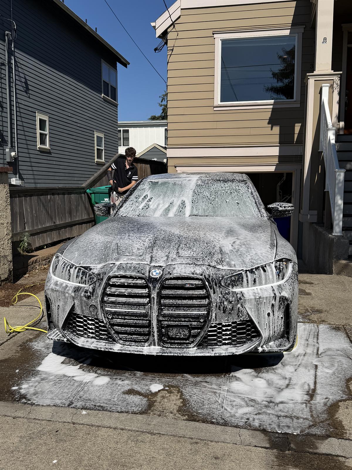 BMW M3 covered in foam mid-wash in a Portland driveway